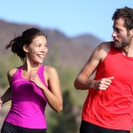 Happy couple running and training outside. Healthy smiling young mixed-race Asian and Caucasian young couple exercising in nature.